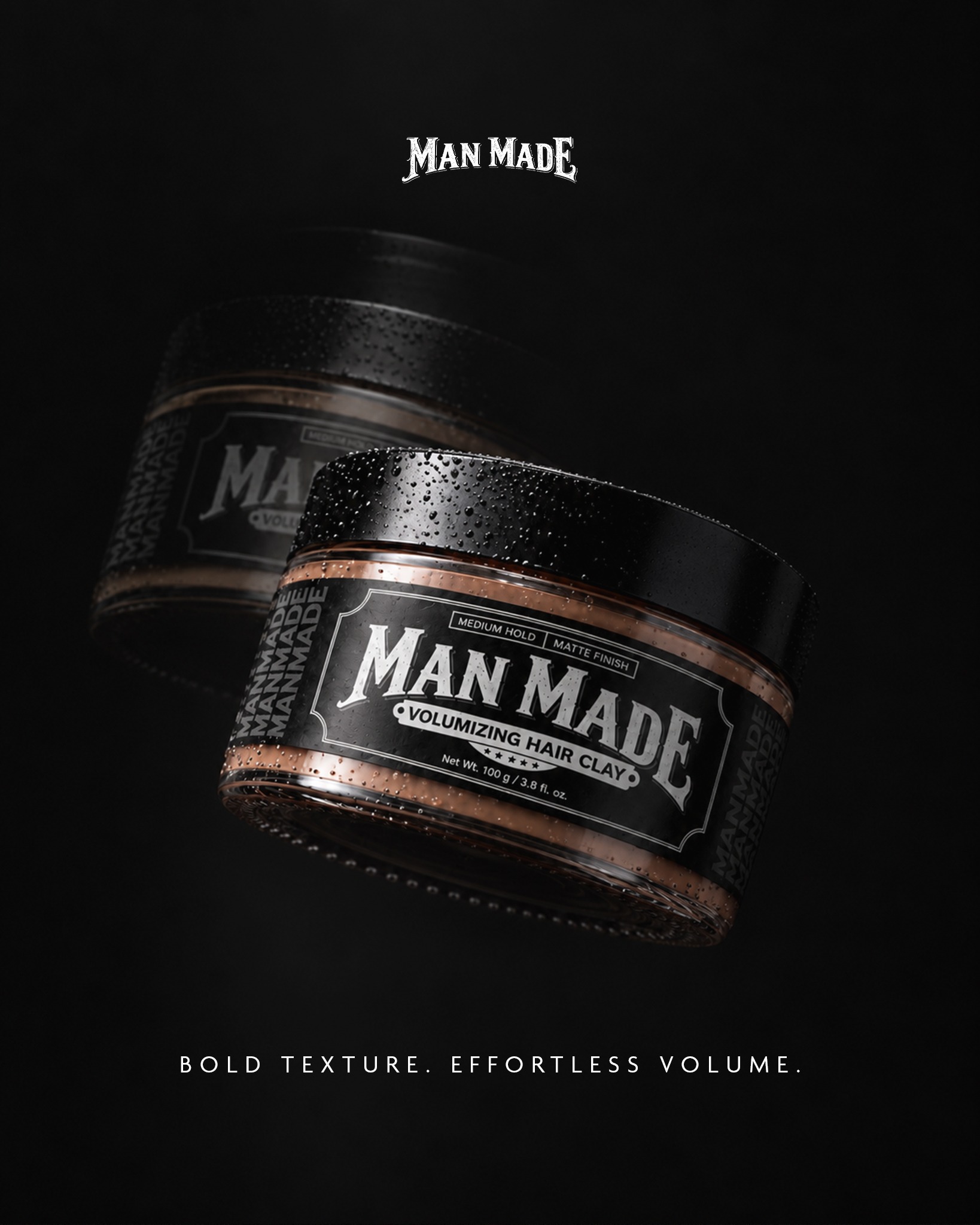 Original Man Made Volumizing Hair Clay campaign photograph, showing two black-lidded jars with copper-toned clay